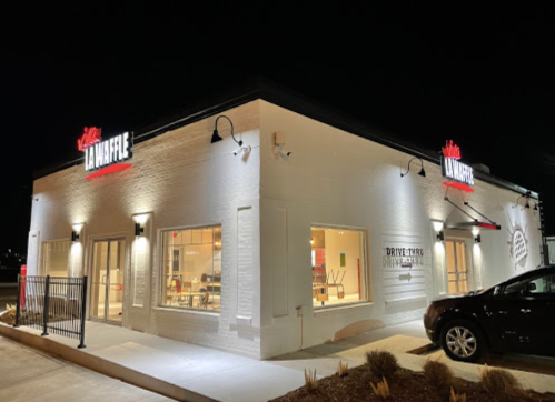 A brightly lit Waffle House restaurant at night, featuring a drive-thru and modern exterior design.