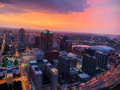 Aerial view of a city skyline at sunset, with vibrant orange and purple hues illuminating the buildings and streets below.