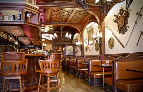 Cozy restaurant interior with wooden decor, bar seating, and medieval-themed wall decorations, including swords and shields.