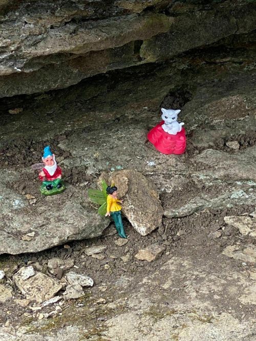 Three small figurines on a rocky surface: a gnome, a fairy, and a princess.