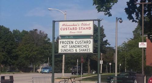 Sign for Milwaukee's Oldest Custard Stand, featuring frozen custard, hot sandwiches, sundaes, and shakes.