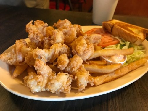 A plate of crispy fried shrimp, French fries, lettuce, tomato, and a slice of toasted bread.