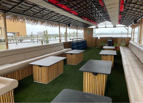 A spacious, covered outdoor seating area with bamboo tables and benches, overlooking a waterfront view.