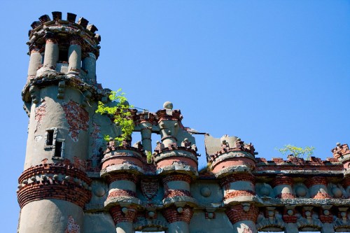 Ruins of a historic building with crumbling walls and greenery growing from the structure against a clear blue sky.