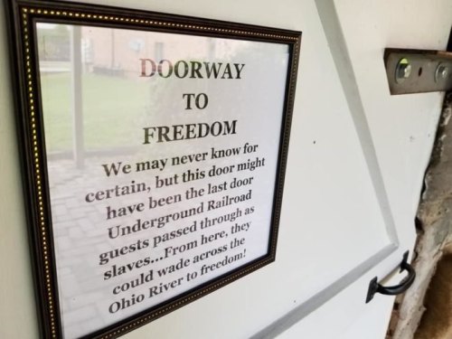 Sign framed on a door, reading "Doorway to Freedom," referencing the Underground Railroad and the Ohio River.