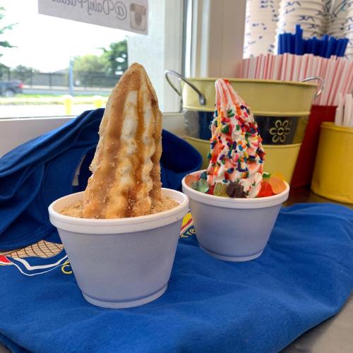 Two ice cream cones in cups: one with a caramel swirl and the other topped with colorful sprinkles and candy.