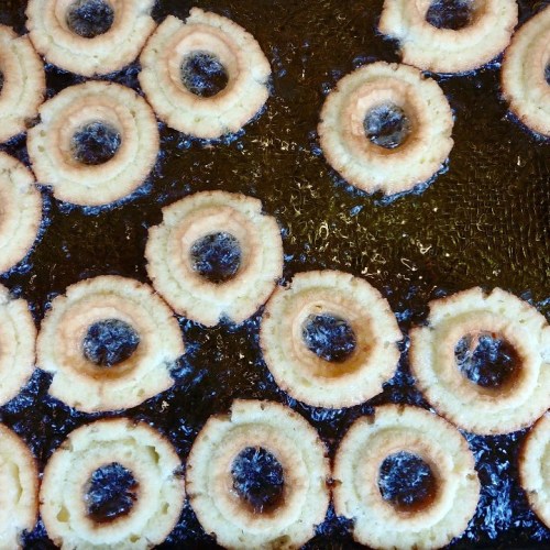 Fried dough rings in hot oil, creating a golden-brown texture with a circular shape and crispy edges.