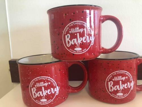 Three red speckled mugs stacked, featuring the logo of "Hilltop Bakery" with the tagline "Where the sweets never end."