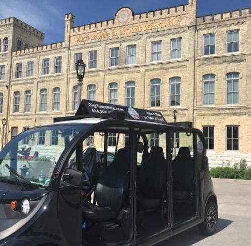A black tour vehicle parked in front of a historic brick building with "Bottling Department" signage.