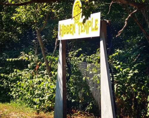 Sign for "Hidden Temple" surrounded by lush greenery and trees.