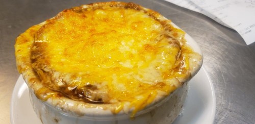 A bowl of bubbling, golden-brown French onion soup topped with melted cheese.
