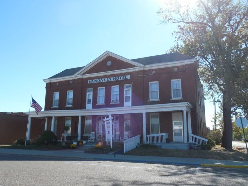 Historic Vandalia Hotel with a brick facade, porch, and American flag, surrounded by autumn decorations.