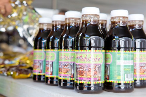 Bottles of sauce lined up on a table, featuring colorful labels with the text "Molokai'z" and "What U See Is What U Get."
