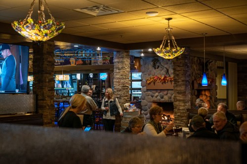 A cozy restaurant interior with stone accents, colorful lighting, and patrons enjoying their meals and conversations.
