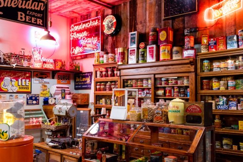 A vintage store filled with colorful cans, jars, and neon signs, showcasing nostalgic items and a warm atmosphere.