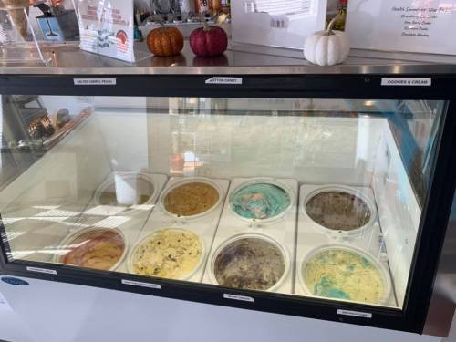 A display case filled with various ice cream flavors, including cookies and cream, and colorful options.