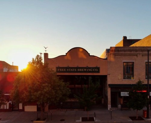Sunset over Free State Brewing Co., a charming building with trees lining the street in a vibrant downtown area.