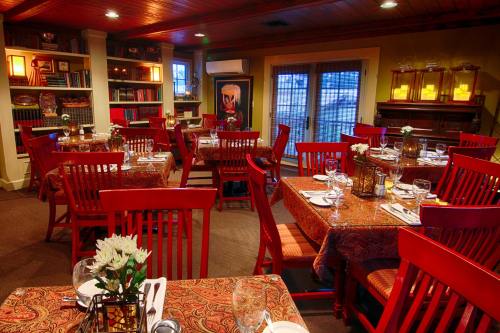 Cozy restaurant interior with red chairs, patterned tablecloths, and warm lighting, set for dining.
