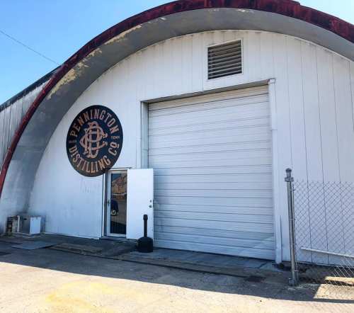 Exterior of Pennington Distilling Co. building with a large logo and a white garage door.