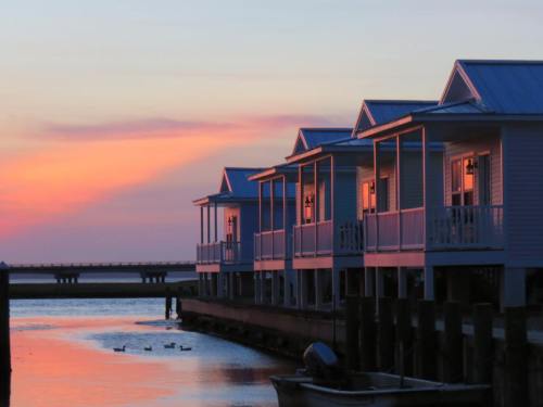 Sunset over waterfront cottages, reflecting warm colors on the water, with ducks swimming nearby.