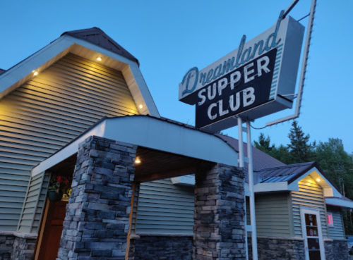 Exterior of Dreamland Supper Club at dusk, featuring a stone facade and a vintage sign.