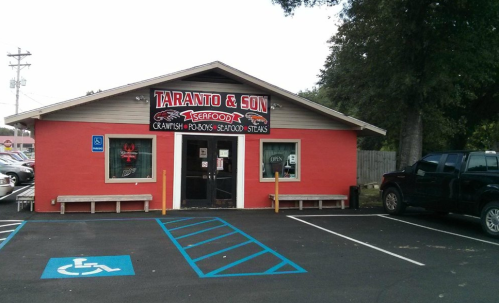Exterior of Taranto & Son Seafood restaurant, featuring a red building with a sign and parking spaces.