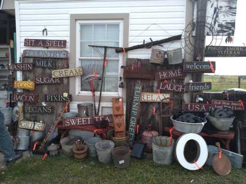 A collection of rustic signs and vintage items displayed against a white wall, featuring phrases like "Sweet Tea" and "Home."