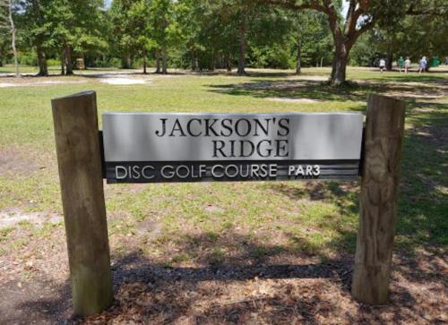 Sign for Jackson's Ridge Disc Golf Course, featuring "PAR 3" in a grassy park setting.