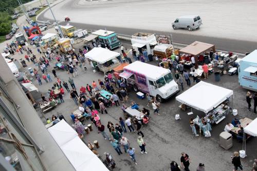 Aerial view of a busy outdoor event with food trucks, tents, and crowds of people enjoying the festivities.