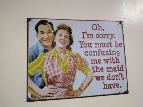 A vintage sign featuring a couple with the text: "Oh, I'm sorry. You must be confusing me with the maid we don't have."