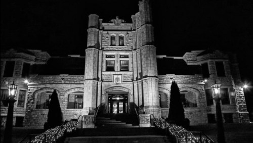 A historic stone building illuminated at night, featuring ornate architecture and decorative lights along the steps.