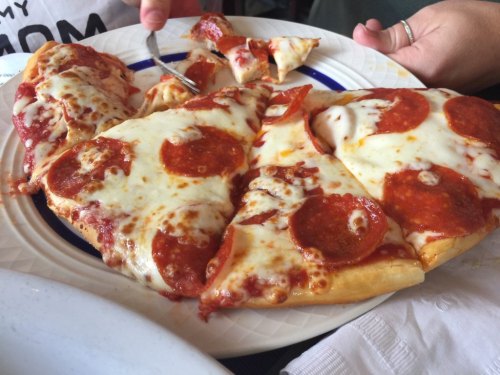 A plate of pepperoni pizza with melted cheese, some slices partially eaten, and a fork in the background.