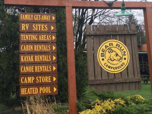 Signpost at Bear Run Campground with directions to RV sites, tenting areas, cabin rentals, and amenities like a heated pool.