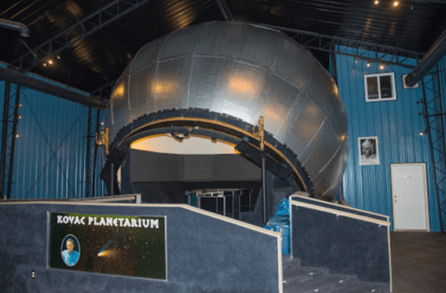 Interior of the Koyac Planetarium featuring a large, metallic dome structure and a dark, modern design.