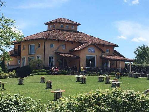 A large, yellow building with a tiled roof, surrounded by green grass and outdoor seating under a clear blue sky.