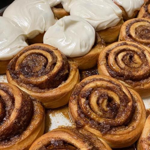 Freshly baked cinnamon rolls with creamy frosting, arranged in a warm, inviting display.