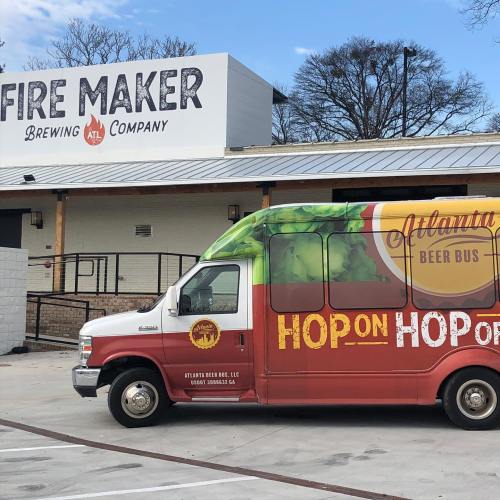 A colorful beer bus parked outside Fire Maker Brewing Company, with a clear blue sky in the background.