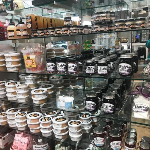 A display shelf filled with various jars and containers of candles, lotions, and other products labeled "Utah."