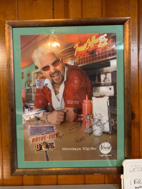 A framed poster of Guy Fieri promoting "Diners, Drive-Ins, and Dives," featuring his signature and a ketchup bottle.