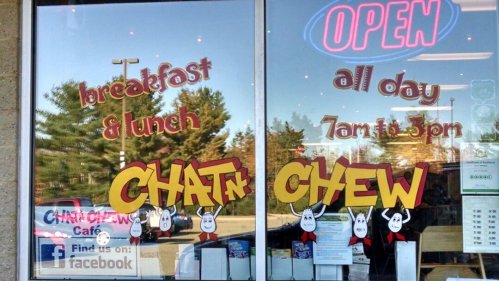 Window display of a café featuring "Chat'n Chew" with hours for breakfast and lunch, and an "Open" sign.