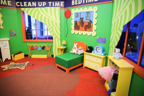 Colorful children's room with green walls, a bed, toys, a clock, and playful decor, creating a cozy atmosphere.
