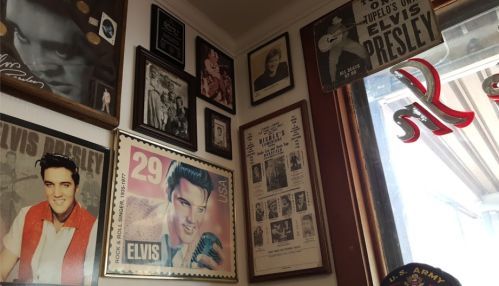 A corner of a room decorated with various Elvis Presley memorabilia and framed photos on the walls.
