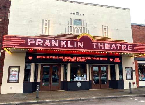 The Franklin Theatre with a marquee displaying a quote and upcoming event details, set in a charming urban area.
