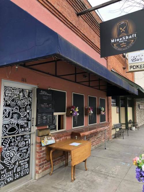 Exterior of the Mine Shaft restaurant, featuring a chalkboard menu, flower pots, and a sign above the entrance.