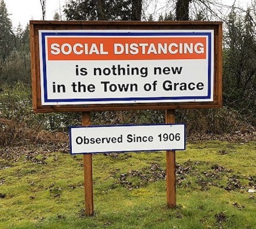 A sign reads "Social Distancing is nothing new in the Town of Grace, Observed Since 1906," set in a grassy area.