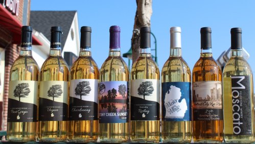 A row of wine bottles with various labels, showcasing different types of white wines against a sunny backdrop.