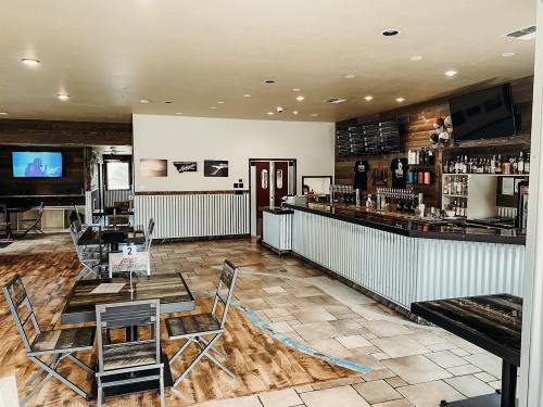 Interior of a modern bar with a wooden counter, tables, and a large TV on the wall. Bright and inviting atmosphere.