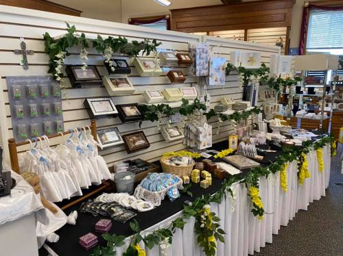 A display of various framed items, gifts, and decorations, adorned with greenery and floral accents.