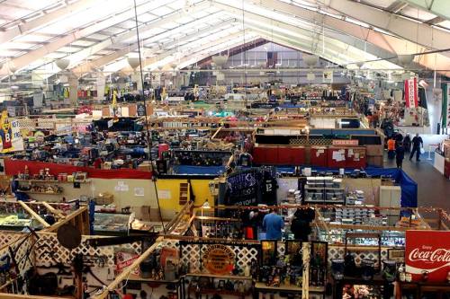 A wide view of a bustling indoor market filled with various stalls and shoppers browsing merchandise.