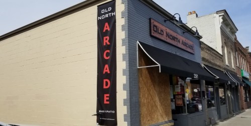 Exterior of Old North Arcade, featuring a sign and a covered window, with a patio area visible.